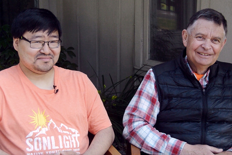 two men smiling sitting on a porch