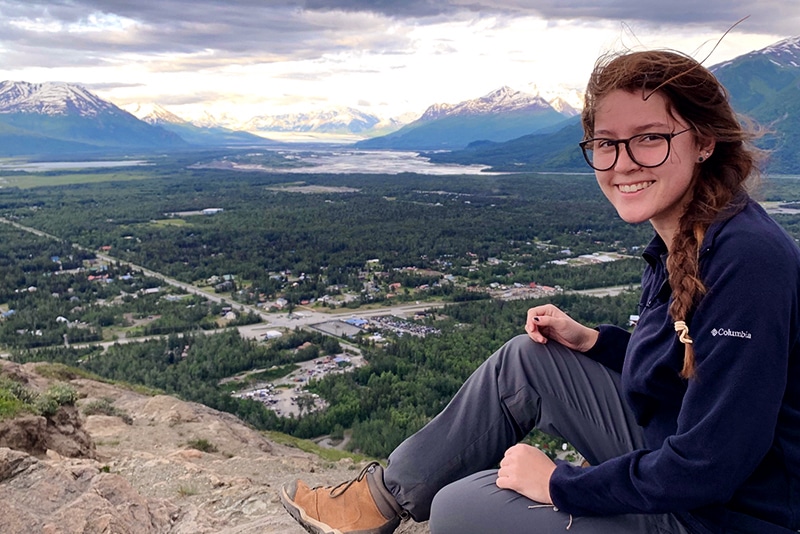 Girl smiling on top of a mountain with a beautiful background