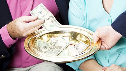 Man putting money into offering plate as it is passed.